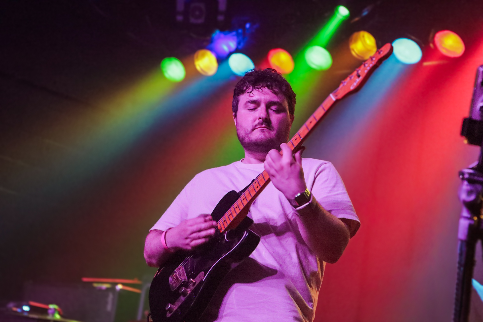 Guitarist performing under colorful stage lights
