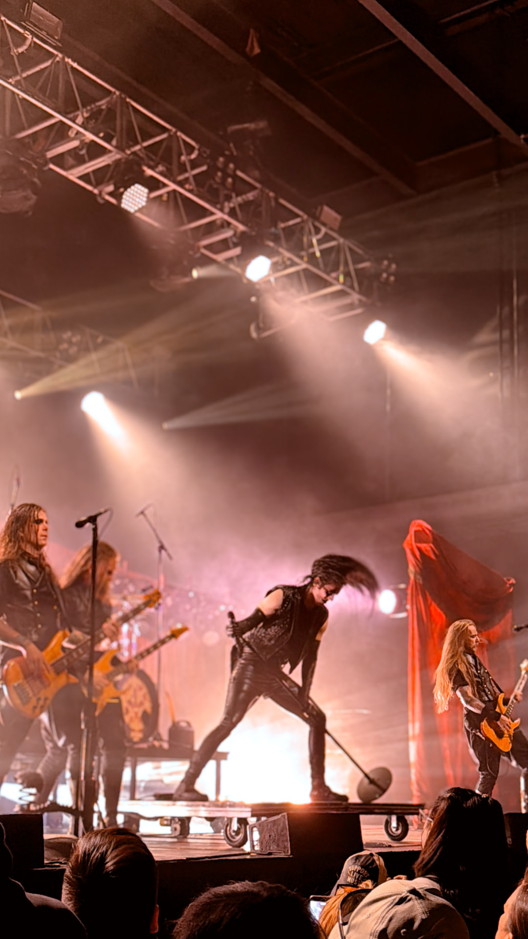 Metal band performing on a smoky stage under red and white lights
