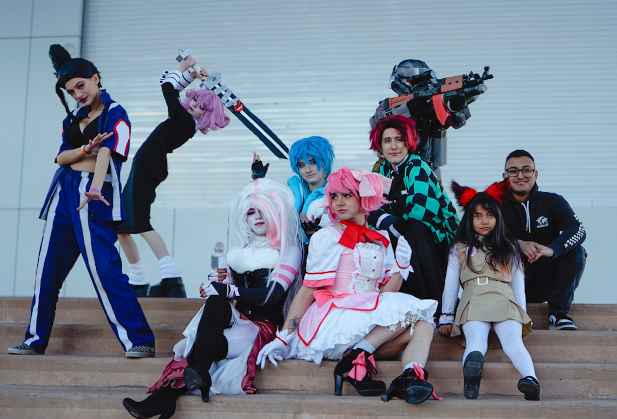 Group of cosplayers in colorful costumes posing on outdoor steps
