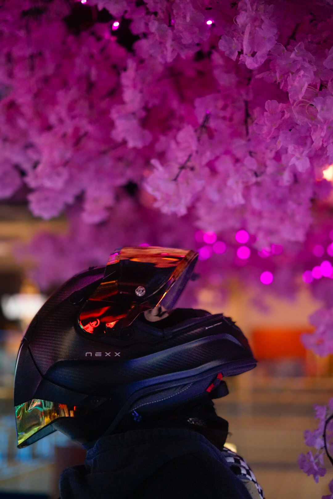 Motorcycle helmet with a red visor beneath pink blossom lights