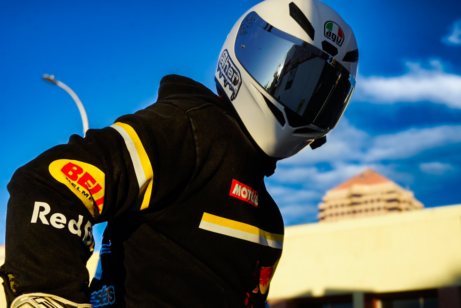 Rider in a white helmet and branded jacket against a bright blue sky