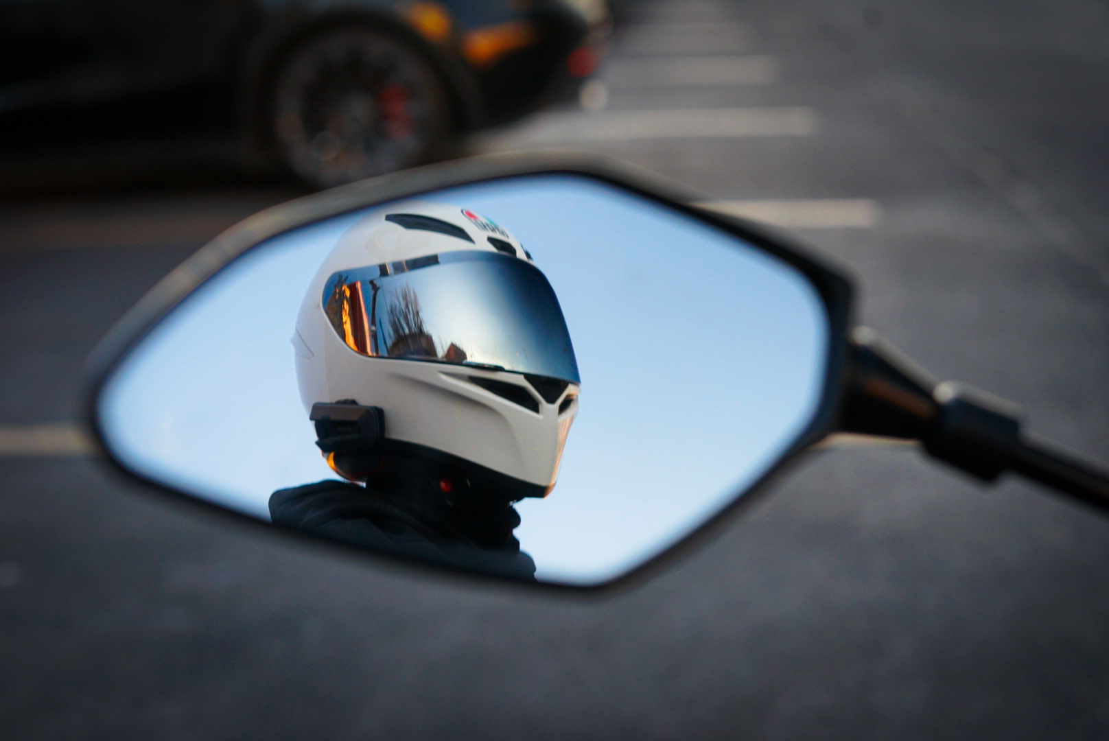 White motorcycle helmet reflected in a bike's rear-view mirror
