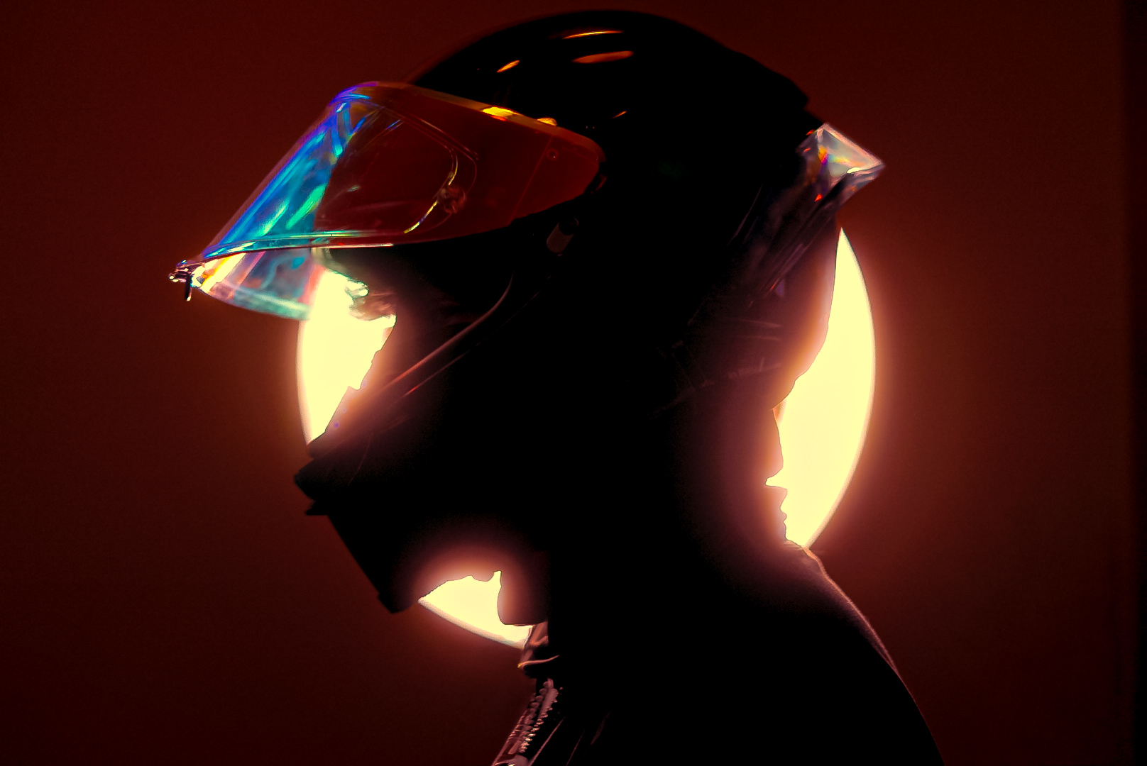 Silhouette of a helmeted rider against a glowing warm light